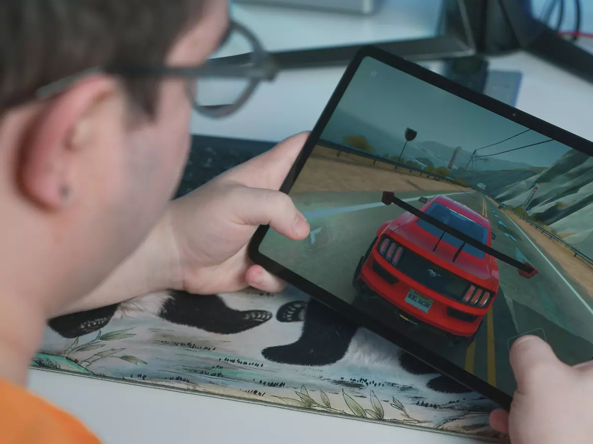 A young man is playing a racing game on a tablet.